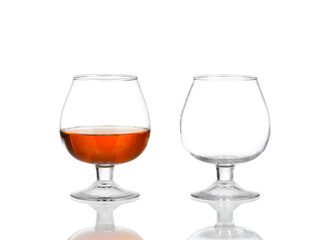 Two brandy glasses (empty and with alcohol) isolated on white background