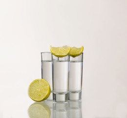 Three gold tequila shots with lime isolated on white background