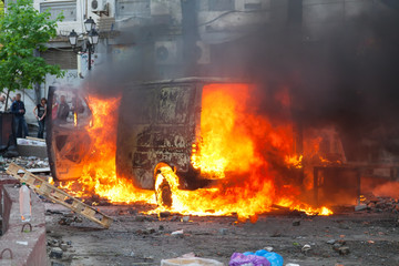 Burning car in the center of city during unrest - 84320144