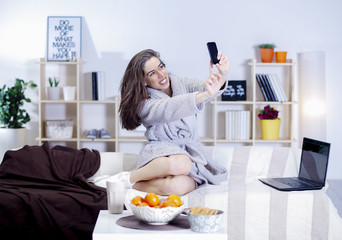 Woman in bed with coffee, tablet, computer, phone laughing