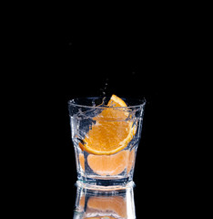 Slice of lemon splashing into a glass of water with a spray of water droplets 