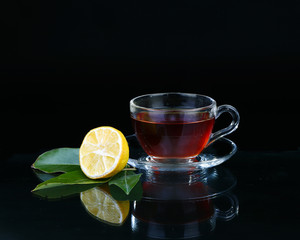 Glass cup of tea on black background.