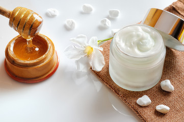 Fototapeta na wymiar Honey moisturizer with stones and flower top view