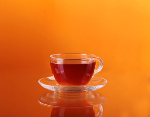 Cup of tea on glass with orange background