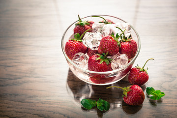 Fresh strawberries with ice cubes in the glass bowl