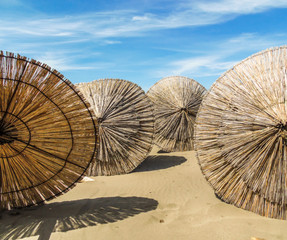 Wooden parasols on sandy seaside