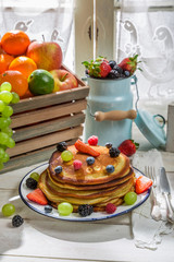 Tasty pancakes with maple syrup and fruits