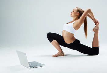 Fototapeta na wymiar Girl makes yoga exercise online with laptop 