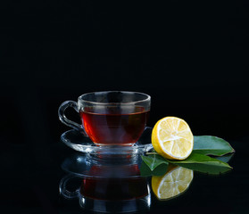 Glass cup of tea on black background.