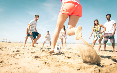 group of friends playing soccer on the beach