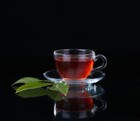 Glass cup of tea on black background.