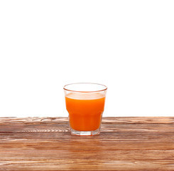 Carrot juice in glass with fresh organic carrots on white wooden table