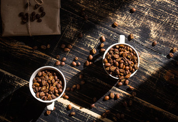 Cups with coffee beans at morning sunlight