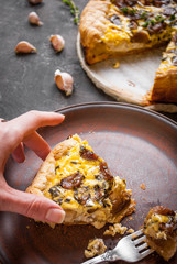 Woman's hand holding a caramelized garlic tart with goat cheese