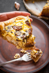Woman's hand holding a caramelized garlic tart with goat cheese