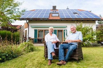 Senior Mann und Frau sitzen im Garten vor Haus