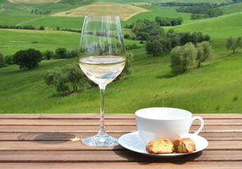 Coffee cup, cantuccini and white wine on the wooden table agains