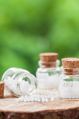 Bottles of homeopathy globules on green background