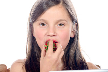 a little girl eating a strawberry