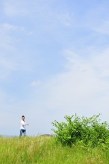 広い青空に向かって手を広げているアジア人の女性