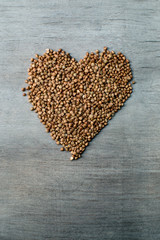 buckwheats grains formed in heart shape on wooden background