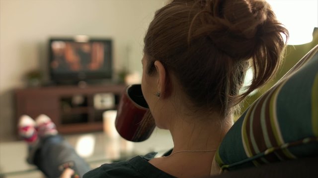 Woman Relax On Sofa Watching Film On TV With Remote