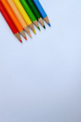 multi colored pencils arranged in a row on drawing paper