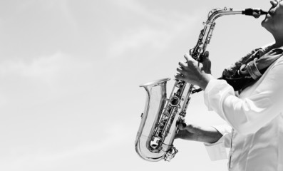 Obraz premium Saxophonist playing on saxophone on blue sky background