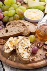 bread with butter, honey, nuts and grapes, vertical