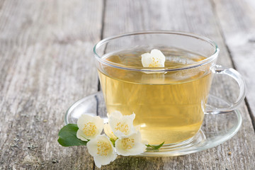 Obraz na płótnie Canvas cup of green tea with jasmine on wooden table, horizontal