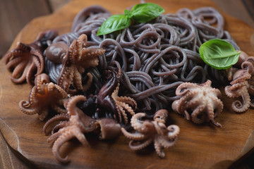 Close-up of baby octopuses with black rice noodles and basil