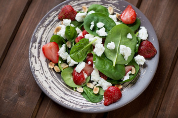 Salad with strawberry, fresh spinach leaves, peanuts and cheese