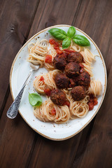 Glass plate with meatballs, spaghetti and green basil, top view