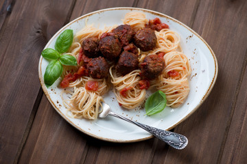 Spaghetti with meatballs and green basil, dark wooden background