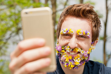 hipster man covered with flowers texting