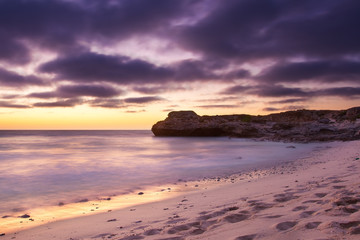 Obraz premium Early morning landscape of ocean over rocky shore and glowing su