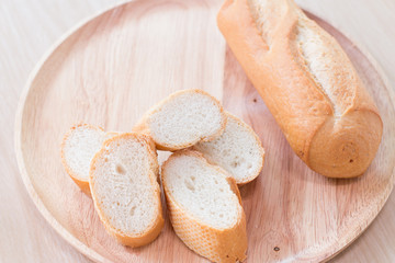 Sliced french bread baguette on wooden plate.Soft focus style