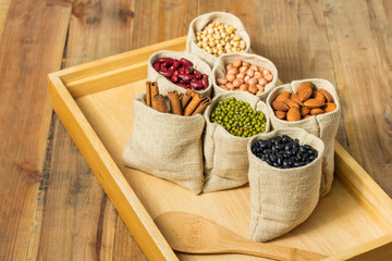 Different kinds of beans in sacks bag on wooden background