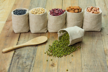 Different kinds of beans in sacks bag, focus on scattered mung beans