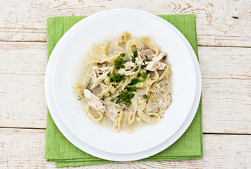 .A bowl of soup with noodles and chicken on a wooden table