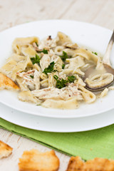 .A bowl of soup with noodles and chicken on a wooden table