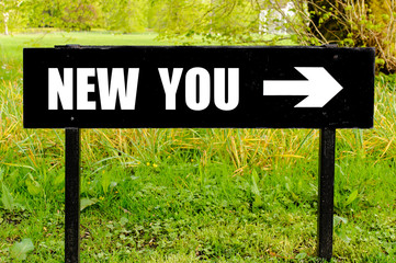 NEW YOU written on directional black metal sign