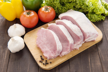 Raw pork on cutting board and vegetables