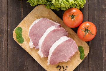Raw pork on cutting board and vegetables