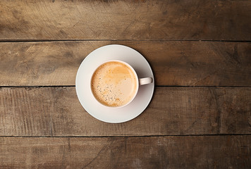 Cup of coffee on wooden table, top view