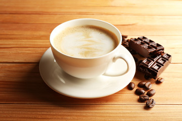 Cup of coffee latte art with grain and chocolate on wooden background