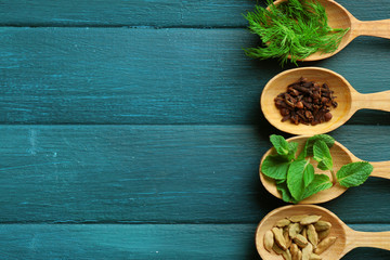 Wooden spoons with fresh herbs and spices on color wooden background