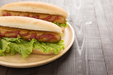 Hot dog with ketchup on wooden background.