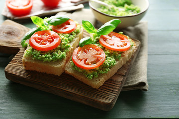 Vegan sandwich with avocado and vegetables on cutting board, on wooden background