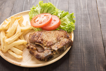 grilled pork chop steak and vegetables with french fries on wood
